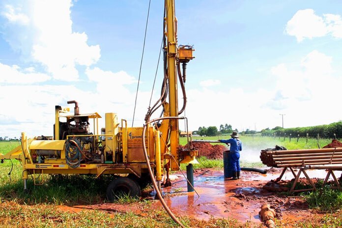 Máquina perfuratriz em ação para construção de poço artesiano Máquina perfuratriz em ação para construção de poço artesiano