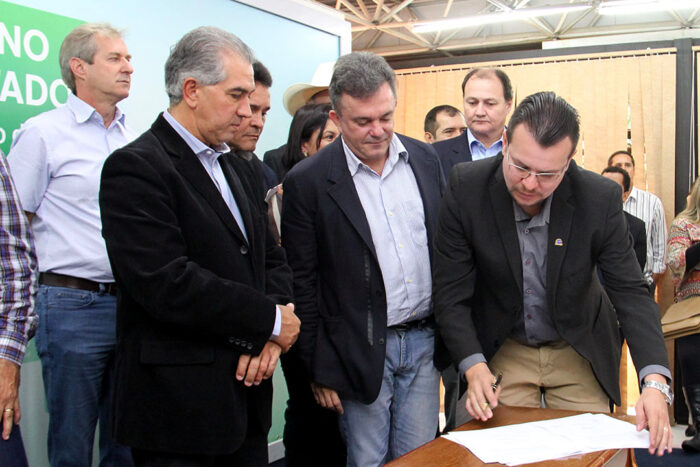 Erney assinando o contrato ao lado de Reinaldo e Vander